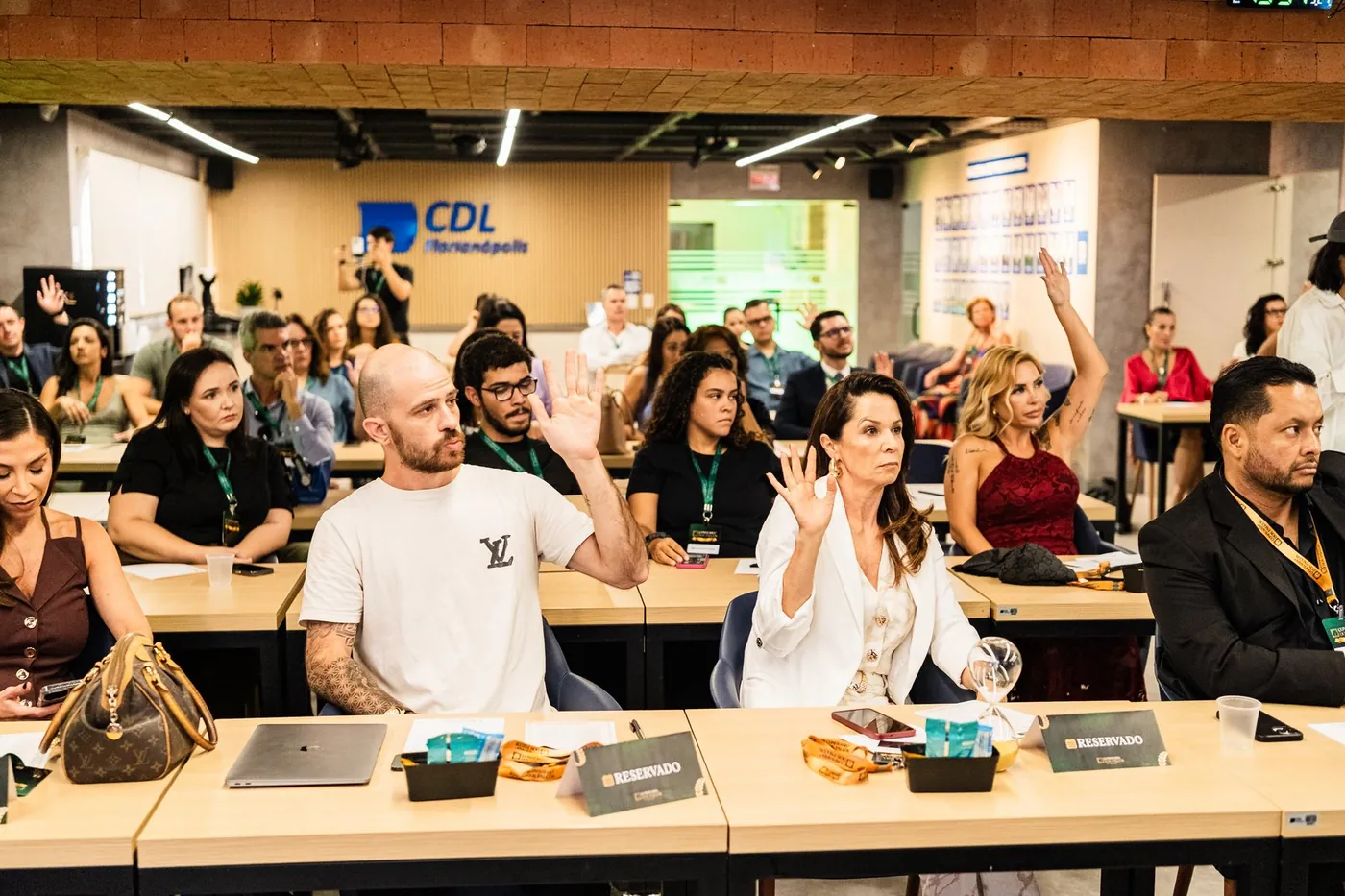 Plateia com as mãos levantadas durante a palestra